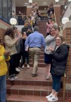 a photo of professor jim levin walking up stairs between lines of applauding students